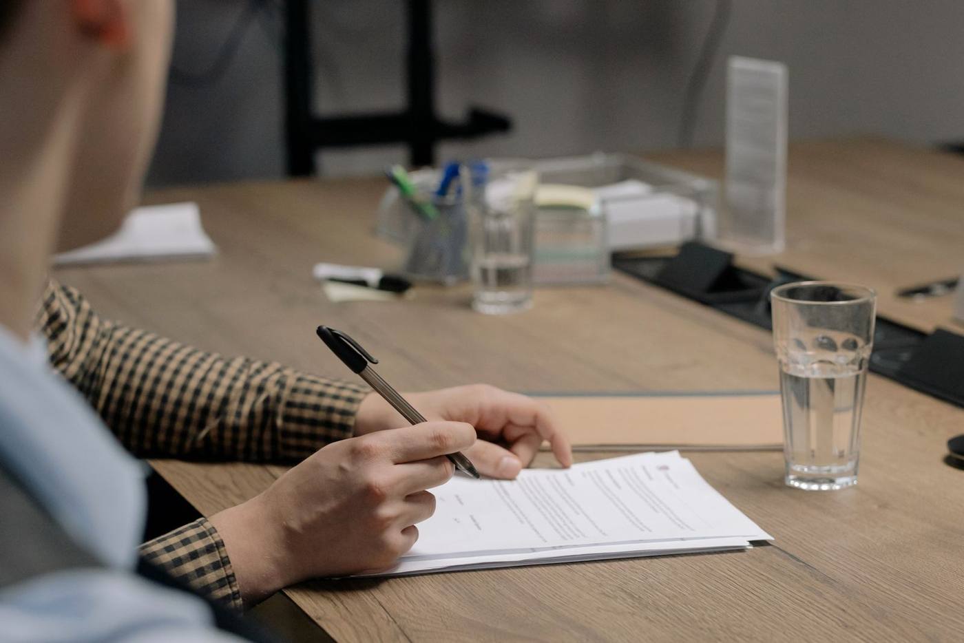 A person reviewing documents and contracts on a laptop screen, at a desk.