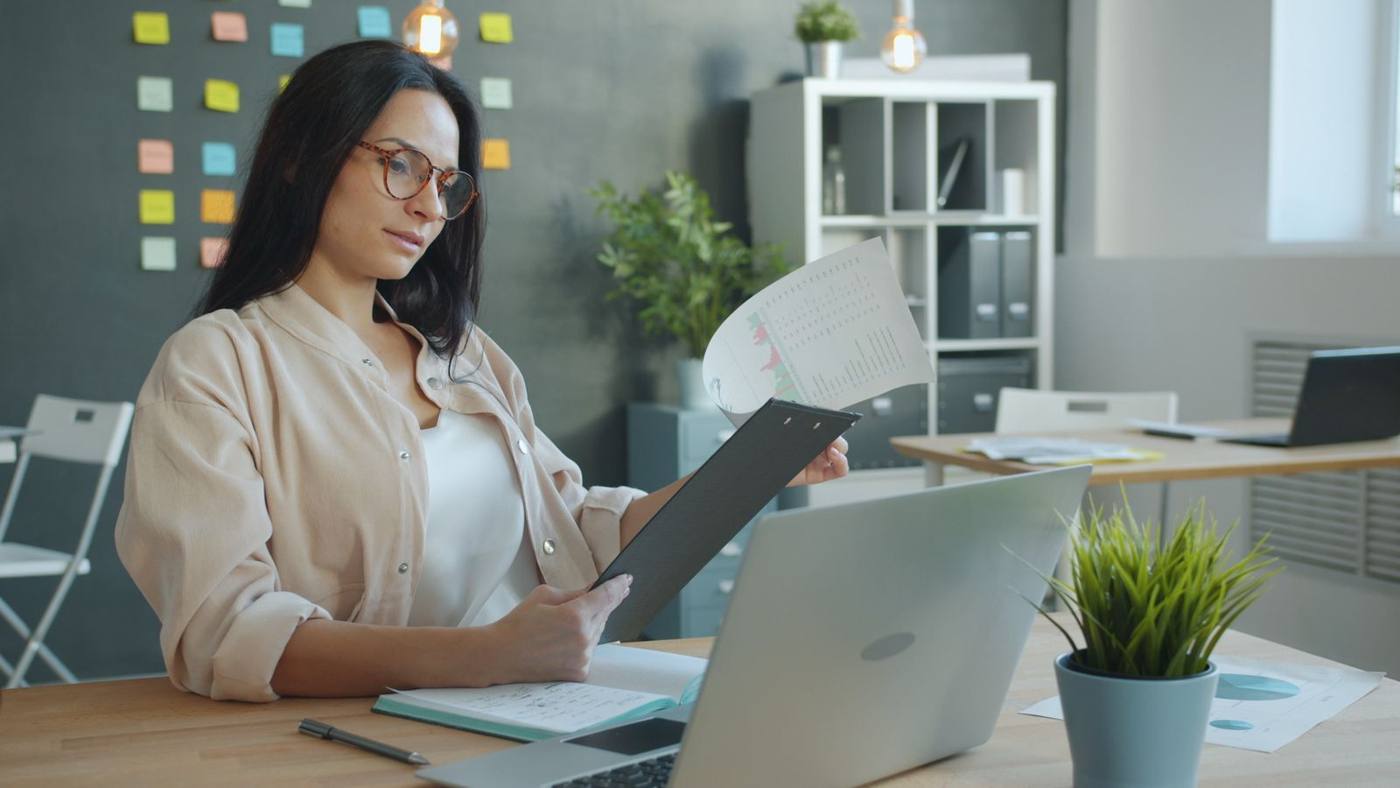 Operations manager checking invoices and reports on a laptop, at the office