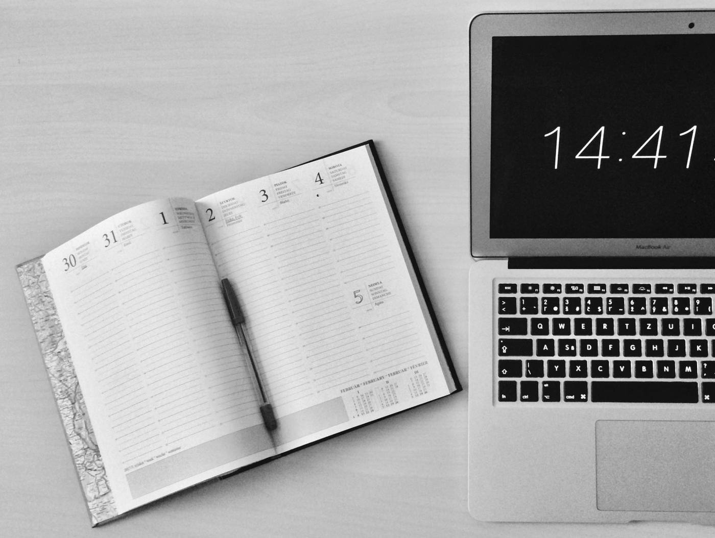 A social media editorial calendar planned on a laptop, next to a notebook.