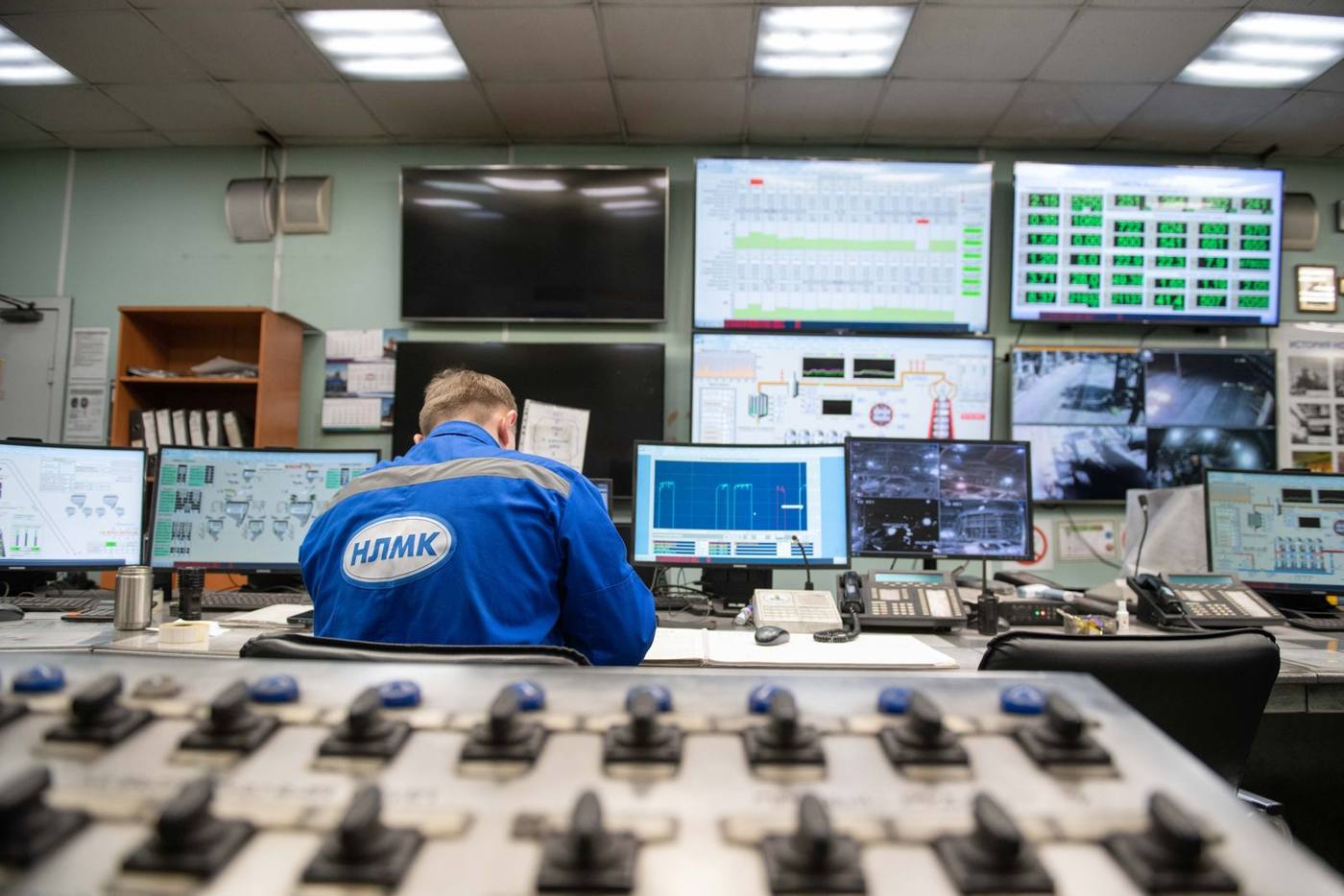 Engineers in an industrial control room analyzing data on large screens.