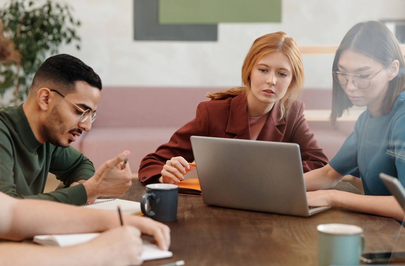 Three colleagues working together on a laptop at an office table