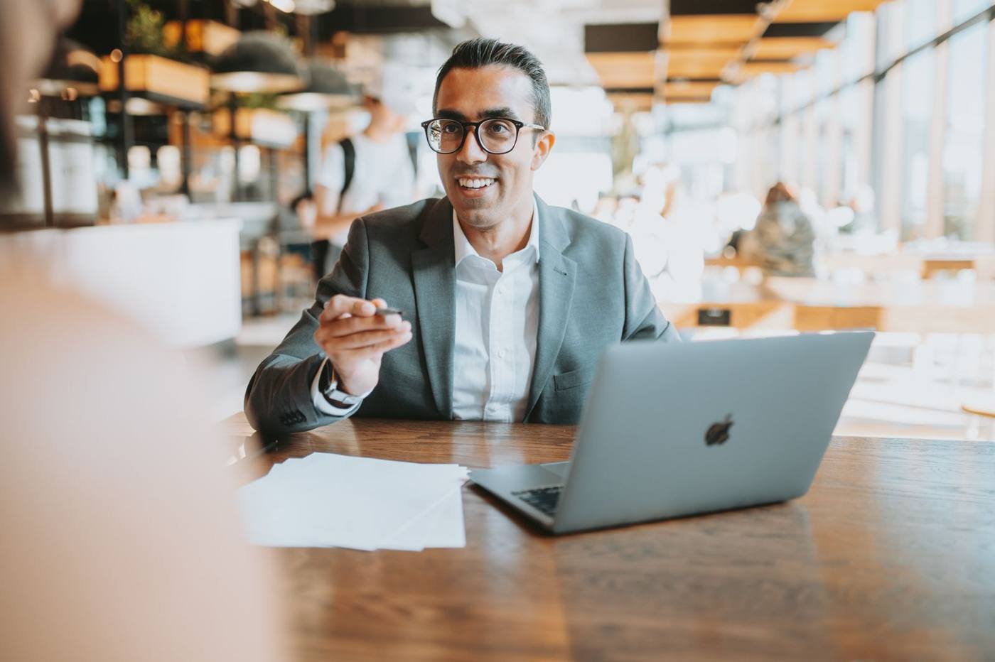 Consultant la o masă cu laptop și hârtii, discutând cu un client