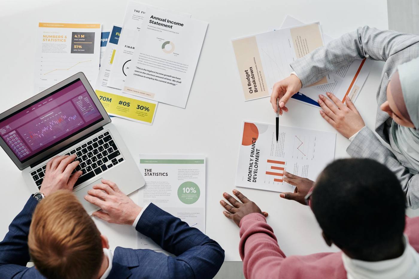 A portfolio review with documents and an open laptop on a meeting table.